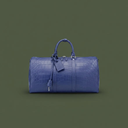 Load image into Gallery viewer, Blue leather duffel bag with crocodile texture on a dark green background