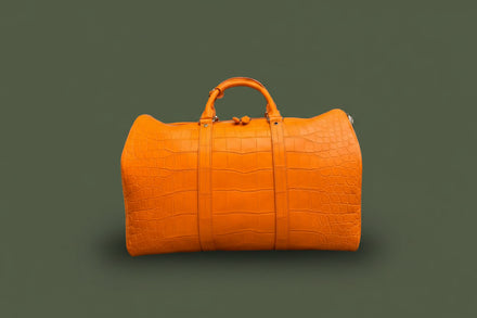 Load image into Gallery viewer, Orange textured handbag on a dark surface with a gray quilted wall background