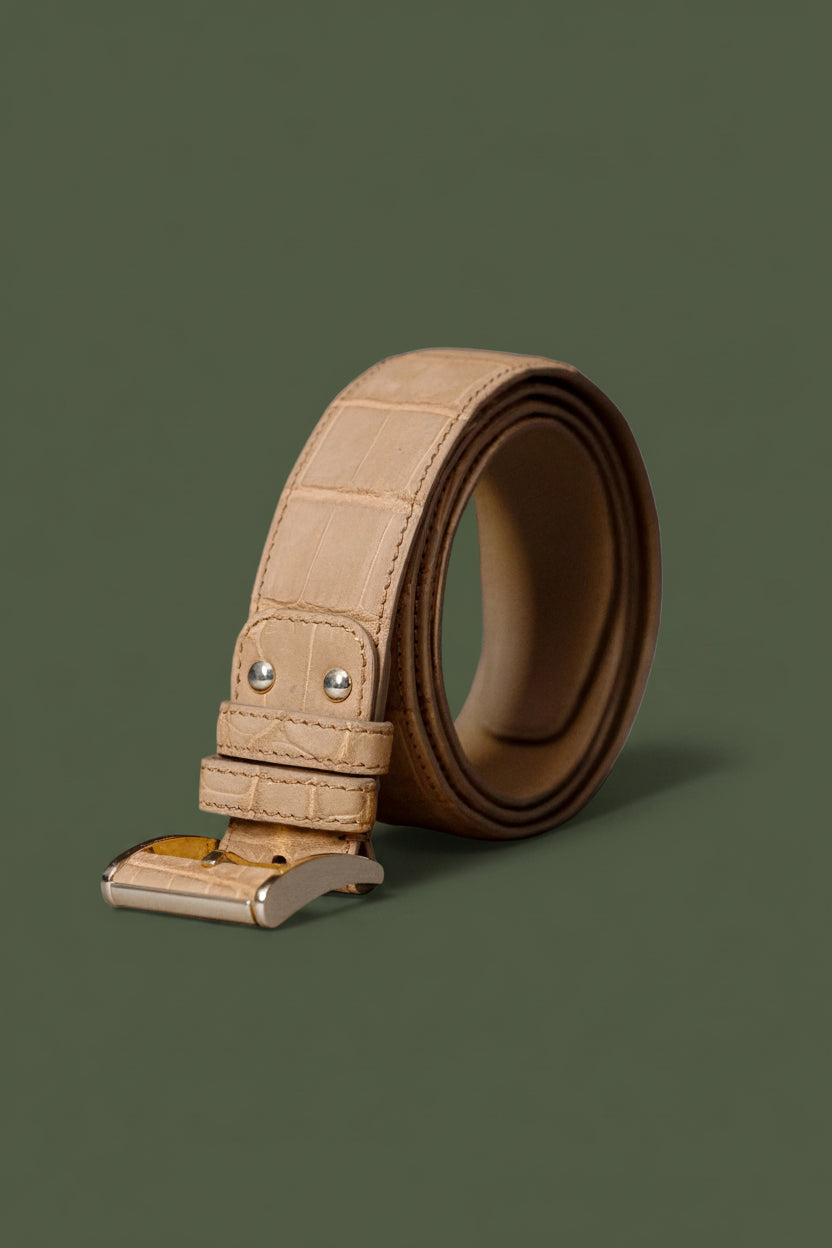 Beige leather belt with a metallic buckle on a white background