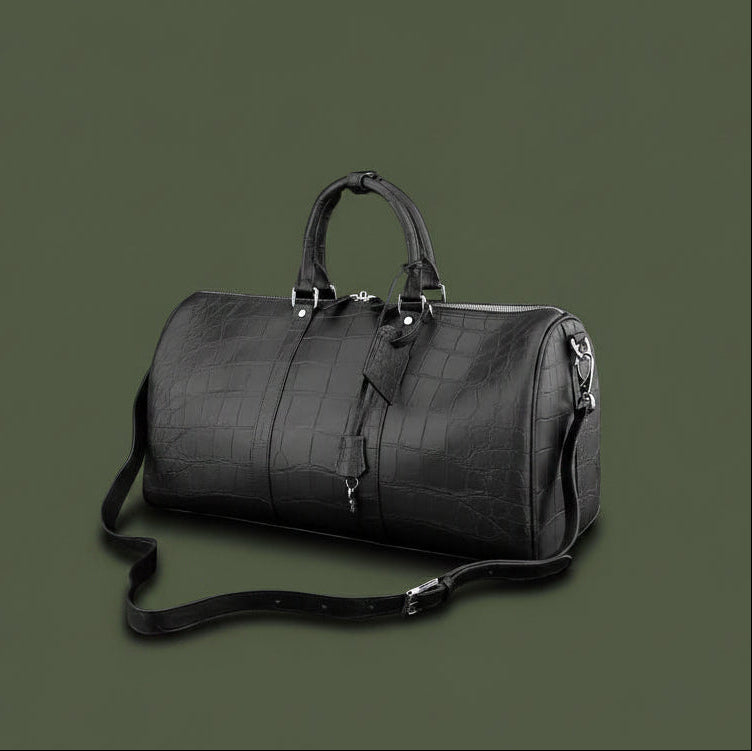 Black leather duffel bag with crocodile texture on a black background